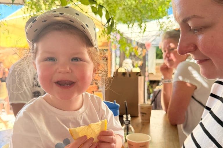 A toddler at a table in Ibiza, holding a slice of lemon